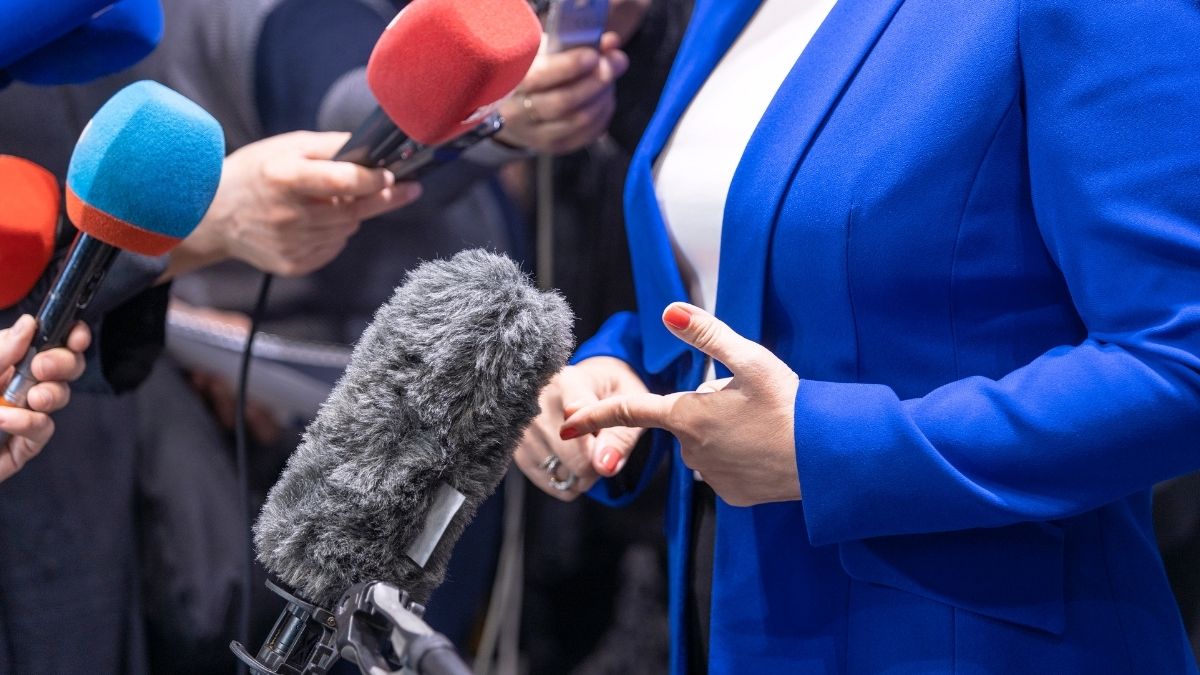 Persona respondiendo preguntas ante varios micrófonos