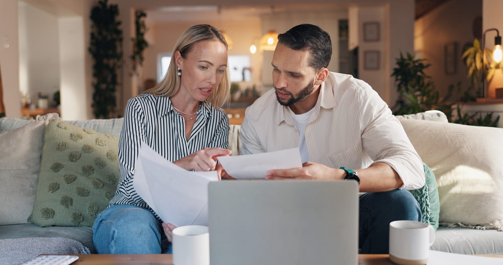 97321512 home couple and laptop with talking for document financial bills and problem solving for budget sofa woman and man with paperwork for tax deduction mortgage expenses or discussio