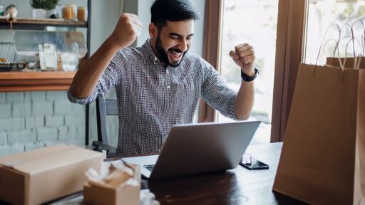 Hombre celebrando éxito frente al portátil