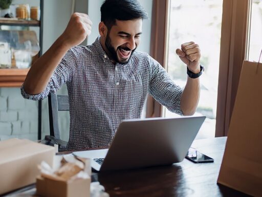 Hombre celebrando éxito frente al portátil