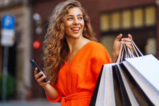 Mujer sonriente con bolsas de compra en la calle