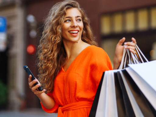 Mujer sonriente con bolsas de compra en la calle