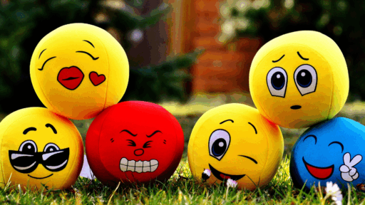 Pelotas con caras de emojis sobre césped