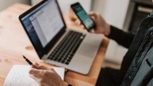 Persona trabajando con portátil y móvil en escritorio