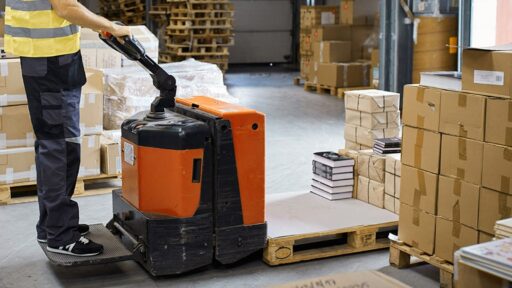 Trabajador moviendo cajas en almacén con montacargas
