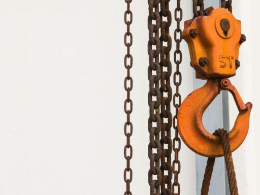 Gancho industrial naranja con cadenas metálicas oxidadas