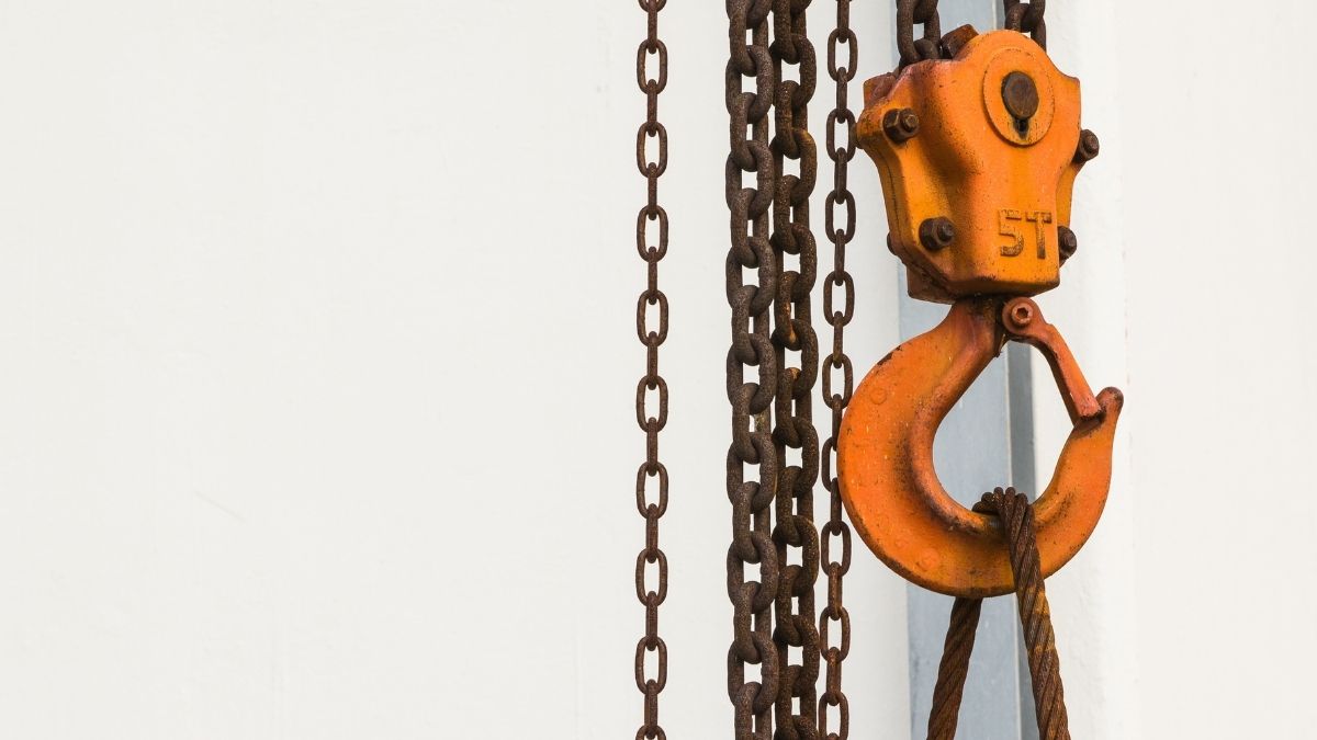 Gancho industrial naranja con cadenas metálicas oxidadas