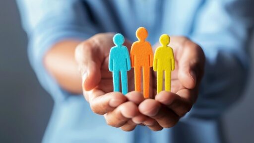 Manos sosteniendo figuras humanas de colores