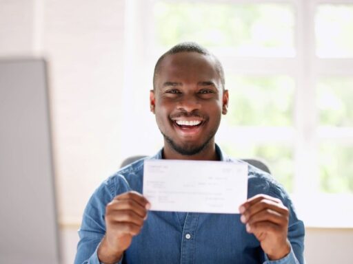 Hombre feliz sostiene un cheque en oficina