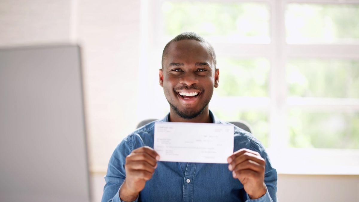 Hombre feliz sostiene un cheque en oficina