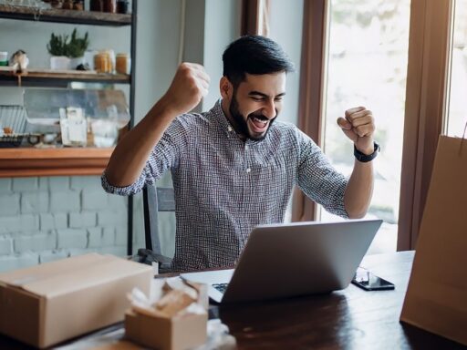 Hombre celebrando éxito frente a su laptop