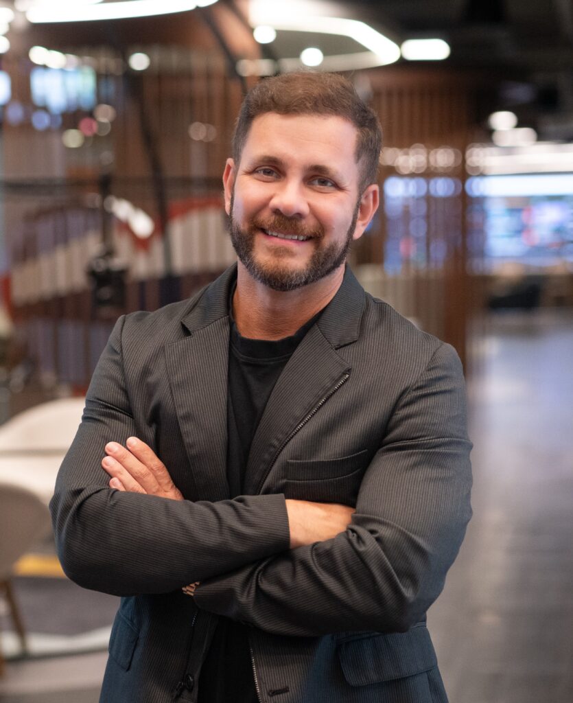 Hombre sonriendo con saco gris en oficina moderna