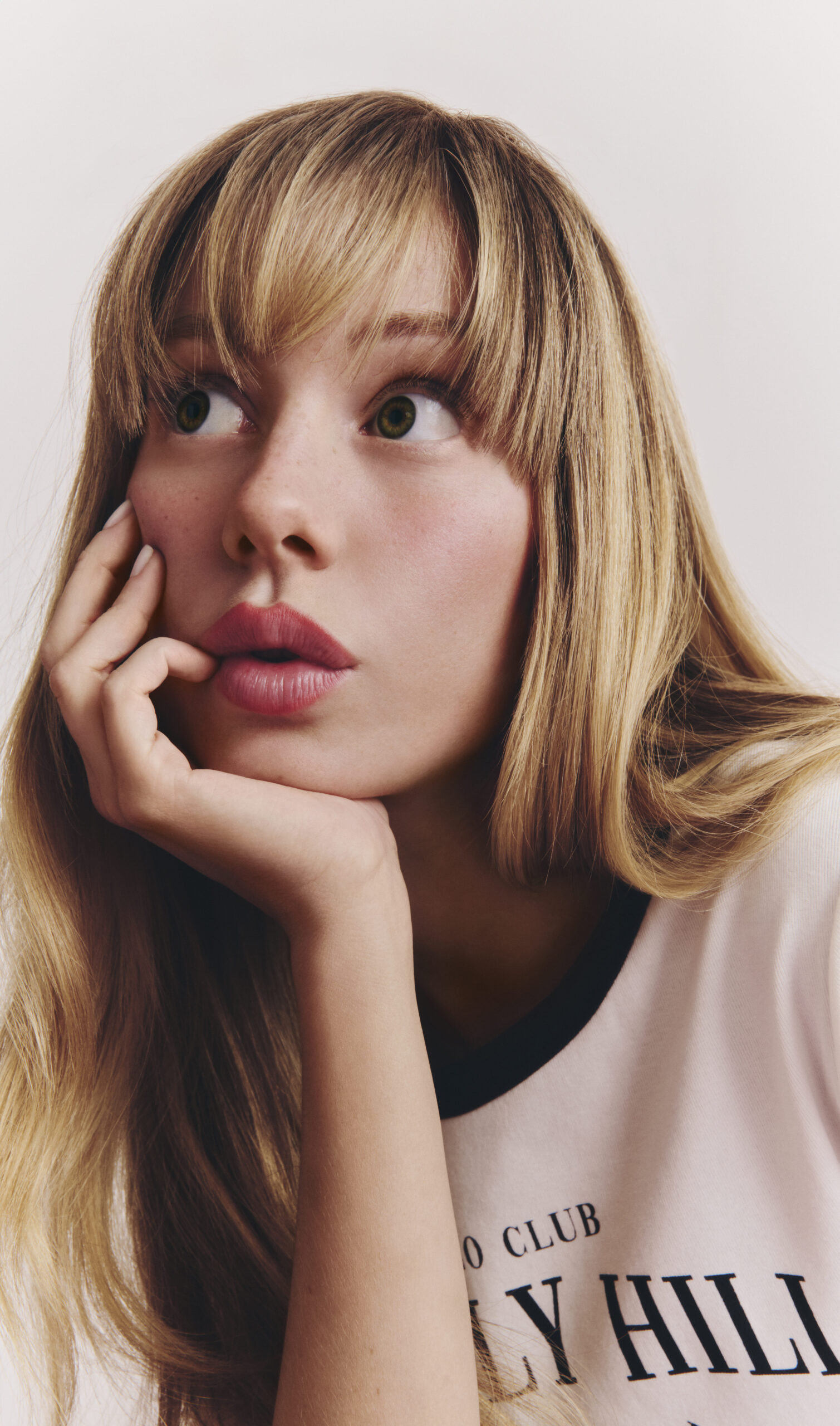 Persona pensativa con camiseta blanca y cabello rubio